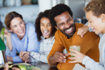 Laughing family drinking healthy green smoothie in kitchen — Stock Photo