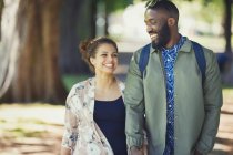 Lächelndes, glückliches junges Paar geht im Park spazieren — Stockfoto