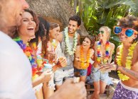 Young friends wearing leis, hanging out at summer poolside — Stock Photo