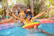 Ritratto esuberanti giovani amici che bevono e giocano in piscina estiva — Foto stock