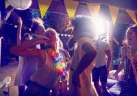 Jeunes amis avec des faveurs de fête dansant et traînant à la fête — Photo de stock
