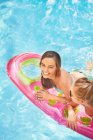 Ritratto sorridente donne amiche galleggianti su zattera in piscina estiva — Foto stock