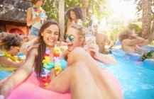 Ritratto entusiasta, ridendo giovani amiche che bevono e giocano in piscina estiva — Foto stock