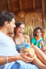 Смеющиеся юные друзья тусуются вместе, пьют кокосовый коктейль у бассейна — стоковое фото