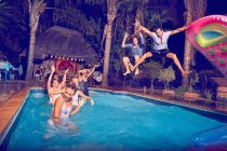 Esuberanti giovani amici che saltano in piscina di notte — Foto stock