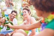 Young friends hanging out, toasting beer bottles in summer park — Stock Photo