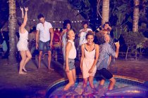 Jovens amigos entusiasmados dançando e saindo na festa de verão à beira da piscina à noite — Fotografia de Stock