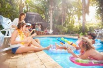Young friends hanging out, playing with squirt gun at summer swimming pool — Stock Photo