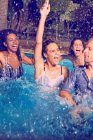 Amici entusiasti che giocano e schizzano in piscina — Foto stock