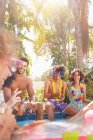Молодые друзья тусуются, разговаривают и пьют в солнечном летнем бассейне — стоковое фото