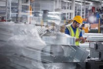 Fabrikarbeiter mit Klemmbrett inspiziert Stahlteile in Fabrik — Stockfoto