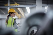 Уверенная женщина-работница с помощью цифрового планшета на сталелитейном заводе — стоковое фото