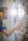 Männlicher Arbeiter mit Ohrenschutz, Bedienung der Maschinen am Schaltschrank in der Fabrik — Stockfoto