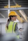 Trabalhadora feminina confiante e sorridente usando tablet digital na fábrica — Fotografia de Stock