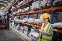 Female worker with clipboard checking inventory in warehouse — Stock Photo