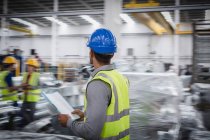 Männlicher Vorgesetzter mit Papierkram läuft in Stahlfabrik — Stockfoto