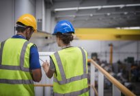 Supervisors discussing paperwork on platform in factory — Stock Photo