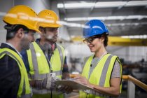 Supervisors with clipboard talking on platform in factory — Stock Photo