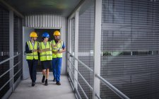 Supervisores com prancheta andando e conversando em passarela elevada fora da fábrica — Fotografia de Stock