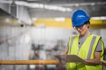 Female supervisor with clipboard on platform in factory — Stock Photo