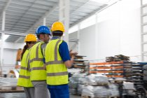 Руководитель и рабочие ходят и разговаривают на складе — стоковое фото