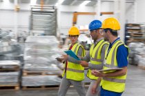 Supervisor and workers walking and talking n warehouse — Stock Photo