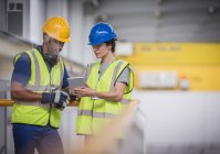 Supervisors with digital tablet talking on platform in factory — Stock Photo