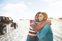 Happy young women friends hugging, enjoying beach road trip — Stock Photo