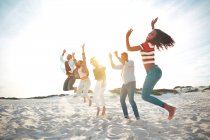 Портрет игривый, энергичные молодые друзья прыгают от радости на солнечном летнем пляже — стоковое фото