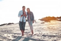 Giovane coppia a piedi sulla spiaggia estiva soleggiata — Foto stock