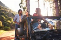 Young friends enjoying road trip in jeep in woods — Stock Photo