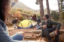 Junge Freunde bauen Lagerfeuer und schlagen Zelt auf Zeltplatz im Wald auf — Stockfoto