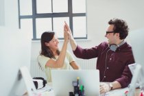Computer programmers high-fiving at laptop in office — Stock Photo