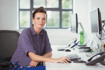 Портрет впевнена бізнес-леді, що працює за комп'ютером в офісі — стокове фото