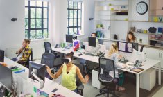 Diseñadores trabajando en escritorios en oficinas de planta abierta - foto de stock