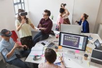Programadores informáticos probando gafas de simulador de realidad virtual en oficinas de planta abierta - foto de stock