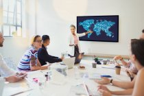 Female designer at television screen leading conference room meeting — Stock Photo