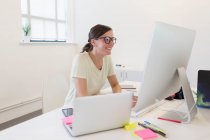 Улыбающаяся деловая женщина, работающая за компьютером в офисе — стоковое фото