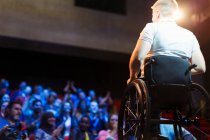 Глядачі чіпляються за жіночого спікера в інвалідному візку на сцені — стокове фото