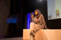 Altoparlante femminile sorridente con microfono in hijab sul palco — Foto stock