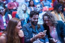 Pessoas de negócios sorrindo usando telefone inteligente no público da conferência — Fotografia de Stock