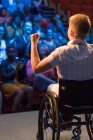 Orador feminino em cadeira de rodas gesticulando no palco para torcer o público — Fotografia de Stock