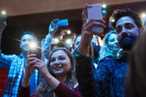 Smiling audience using smart phone flashlights — Stock Photo