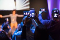 Аудитория с телефонами, фотографирующими спикера на сцене — стоковое фото