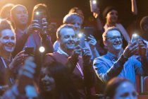 Audiencia sonriente usando linternas de teléfonos inteligentes - foto de stock