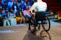 Auditoire regardant une oratrice en fauteuil roulant sur scène — Photo de stock