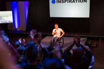 Female speaker in wheelchair on stage talking to audience — Stock Photo