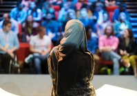 Женщина-оратор в хиджабе на сцене разговаривает с аудиторией — стоковое фото