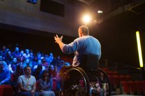 Глядачі спостерігають, як спікер чоловічої статі у інвалідному візку говорить на сцені — стокове фото