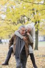 Verspieltes Seniorenpaar huckepack im Herbstpark — Stockfoto